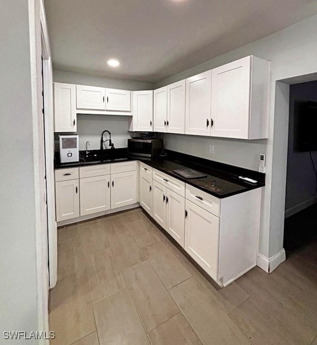 kitchen featuring stainless steel microwave, a sink, and white cabinetry