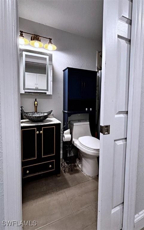 bathroom with a textured wall, vanity, and toilet