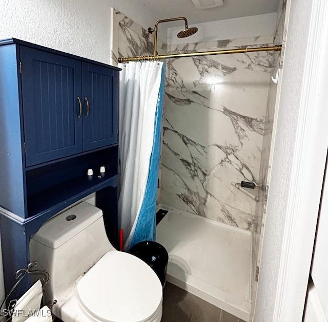 full bath with toilet, a marble finish shower, and a textured wall