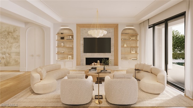 sitting room featuring built in shelves, a notable chandelier, a premium fireplace, wood finished floors, and baseboards