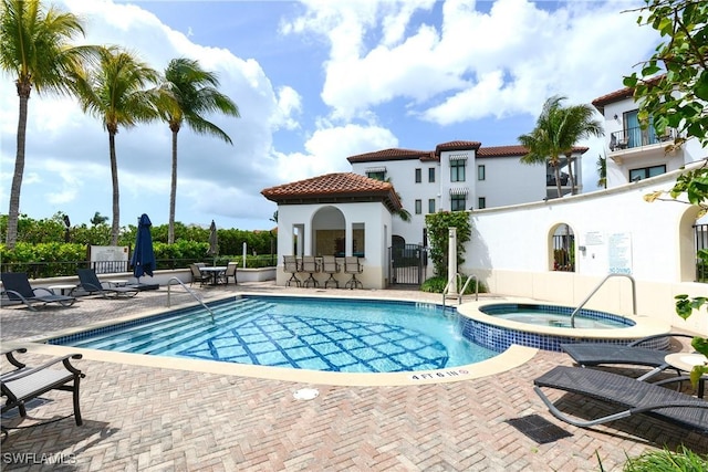 pool with a patio area, fence, and a hot tub