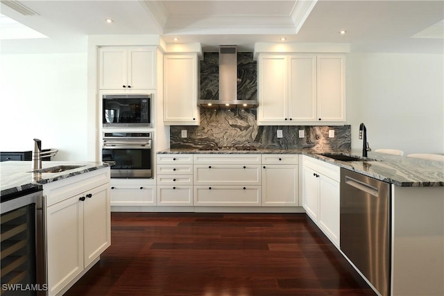 kitchen with wine cooler, a sink, appliances with stainless steel finishes, wall chimney range hood, and tasteful backsplash