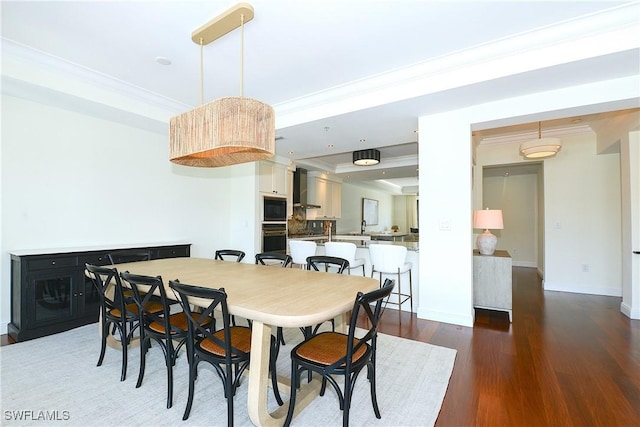 dining room with ornamental molding, baseboards, and wood finished floors