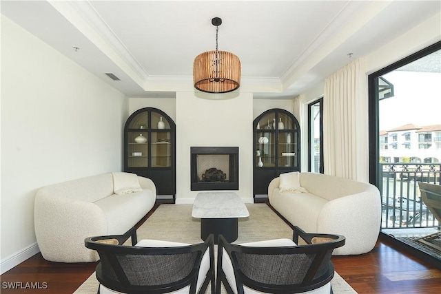 sitting room with crown molding, a raised ceiling, visible vents, wood finished floors, and baseboards