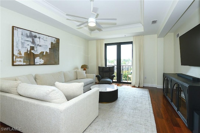 living room with dark wood-style floors, a raised ceiling, visible vents, ceiling fan, and baseboards