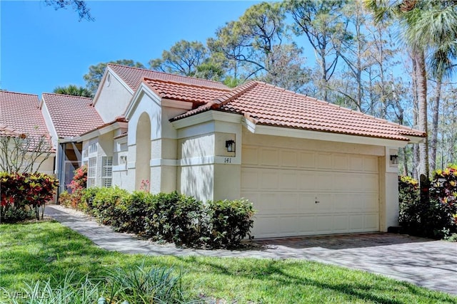 view of front facade featuring an attached garage, a tile roof, and stucco siding