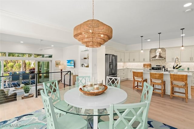 dining room featuring ornamental molding, light wood-type flooring, and recessed lighting