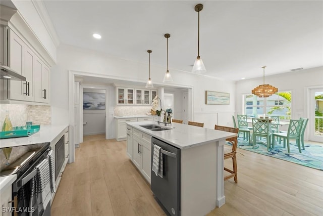 kitchen featuring appliances with stainless steel finishes, white cabinets, a sink, and light wood finished floors