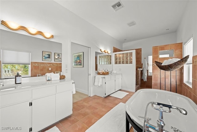 bathroom with two vanities, visible vents, tile patterned flooring, walk in shower, and a bath