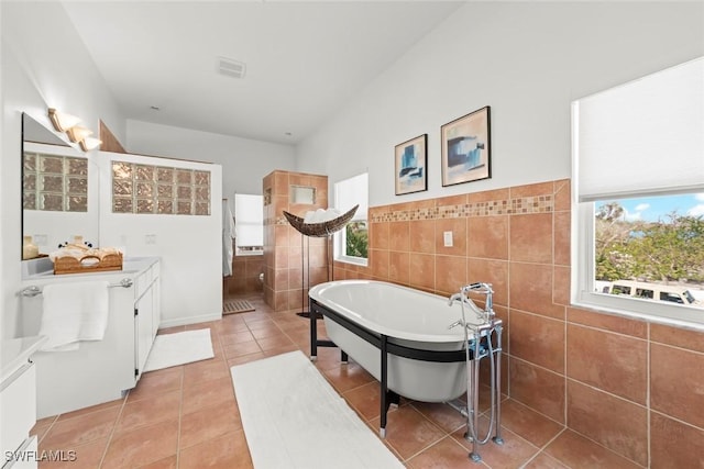 bathroom with visible vents, a healthy amount of sunlight, tile walls, and tile patterned floors