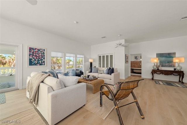 living room featuring ceiling fan, light wood finished floors, and visible vents