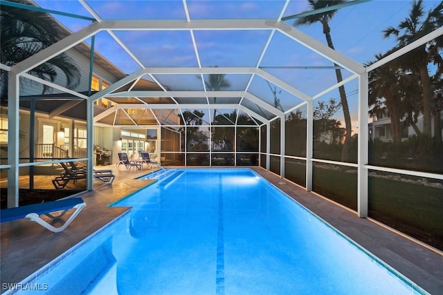 outdoor pool with a patio area and glass enclosure