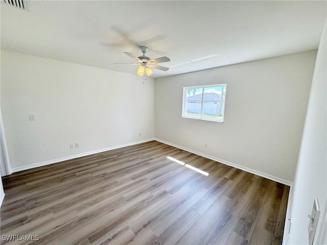 unfurnished room with visible vents, ceiling fan, baseboards, and wood finished floors