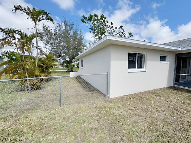 view of side of home featuring a yard, fence, and stucco siding