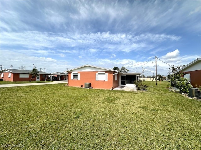 rear view of house with a sunroom, a lawn, and central air condition unit