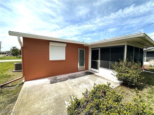 rear view of property featuring a sunroom, a patio area, and cooling unit