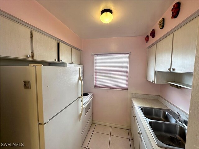 kitchen with light tile patterned flooring, white appliances, a sink, baseboards, and light countertops