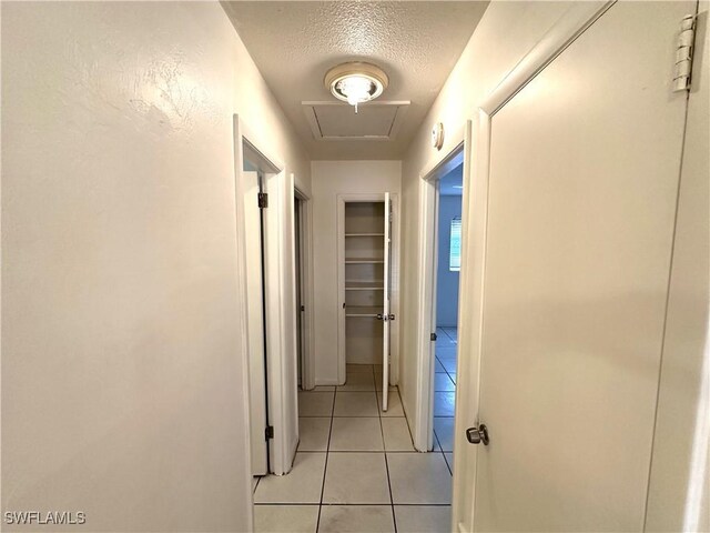 corridor featuring light tile patterned floors and a textured ceiling