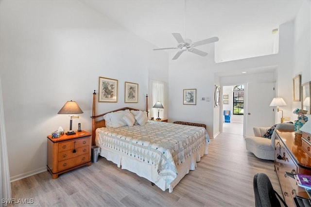 bedroom with light wood-style floors, a towering ceiling, and baseboards