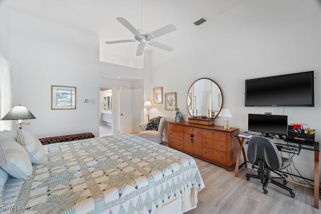 bedroom featuring light wood-style floors, visible vents, ceiling fan, and a towering ceiling