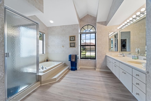 bathroom with lofted ceiling, wallpapered walls, a garden tub, and a sink