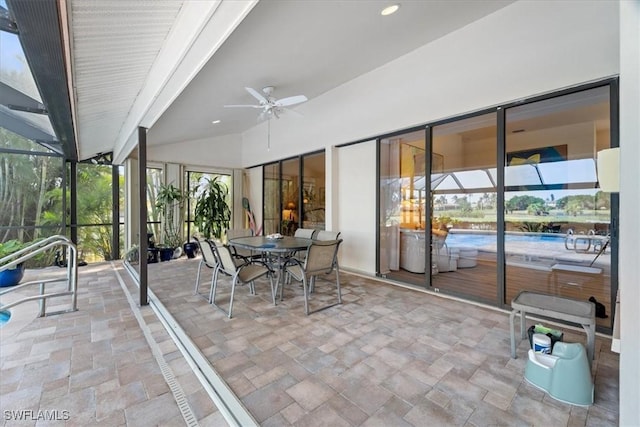 view of patio / terrace featuring a ceiling fan, outdoor dining area, and glass enclosure