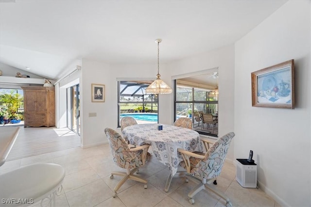 dining area featuring a sunroom, light tile patterned flooring, vaulted ceiling, and baseboards