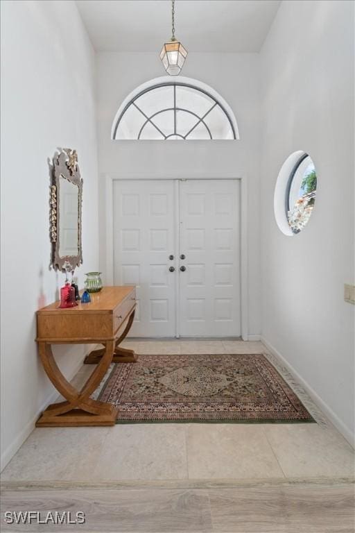 entrance foyer featuring a towering ceiling, baseboards, and tile patterned floors