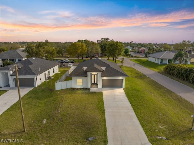 view of front of property with driveway, a residential view, fence, and a yard