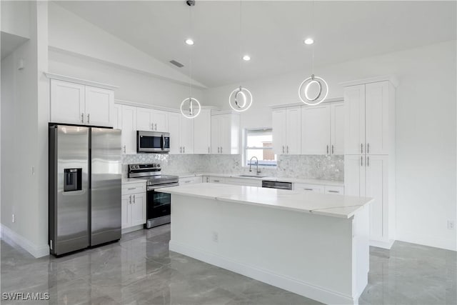 kitchen featuring a center island, light countertops, decorative backsplash, appliances with stainless steel finishes, and a sink