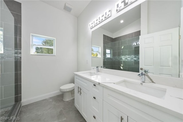 bathroom with toilet, double vanity, a tile shower, and a sink