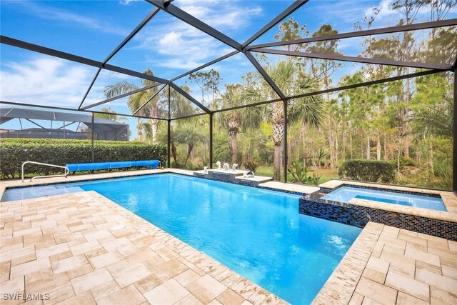 view of pool with a patio area, a pool with connected hot tub, and glass enclosure