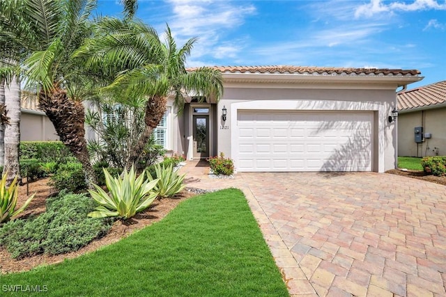 view of front facade with stucco siding, an attached garage, a tiled roof, and decorative driveway