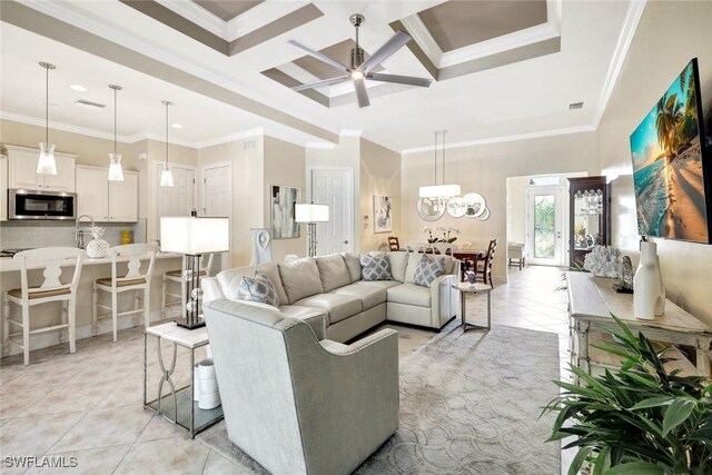 living area featuring light tile patterned flooring, crown molding, ceiling fan, coffered ceiling, and a chandelier