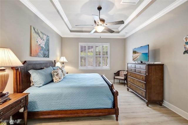 bedroom with baseboards, a raised ceiling, light wood-style flooring, and crown molding