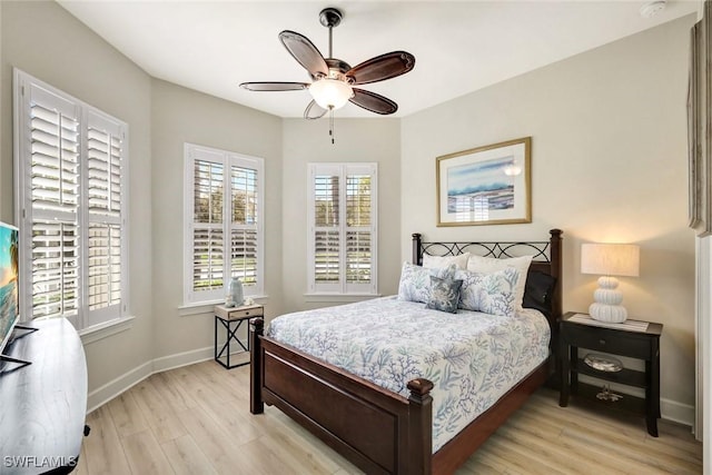 bedroom with light wood finished floors, a ceiling fan, and baseboards