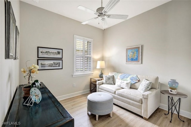 living area featuring light wood-type flooring, a ceiling fan, and baseboards