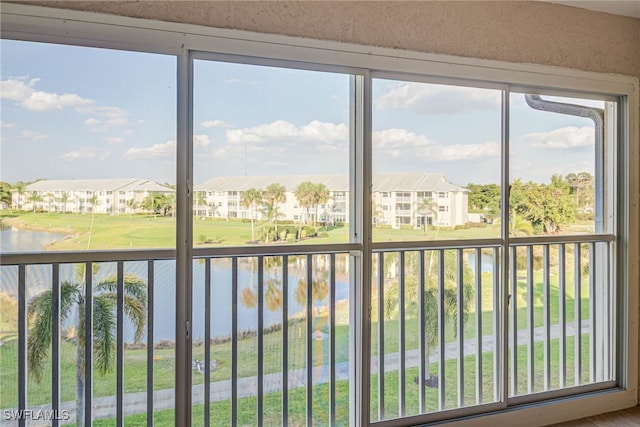 unfurnished sunroom featuring a water view and a residential view