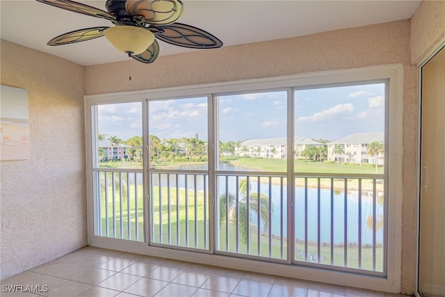 unfurnished sunroom featuring a ceiling fan and a water view