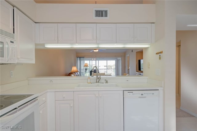 kitchen with a sink, visible vents, white appliances, and white cabinetry