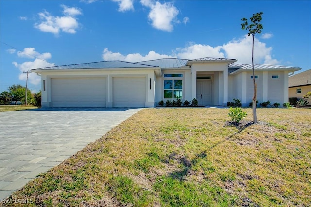 prairie-style house featuring a front lawn, a standing seam roof, decorative driveway, and an attached garage