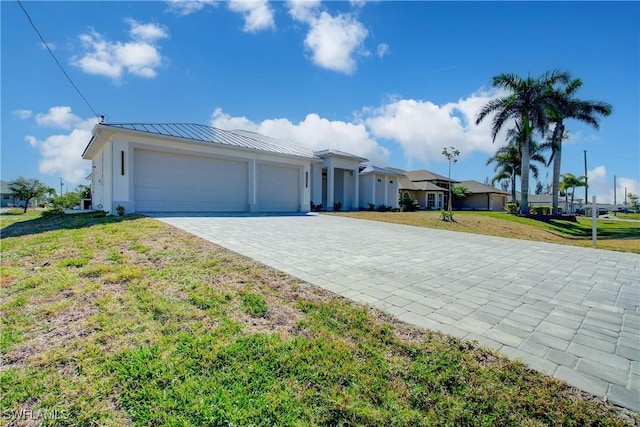 single story home with metal roof, an attached garage, decorative driveway, a standing seam roof, and a front yard