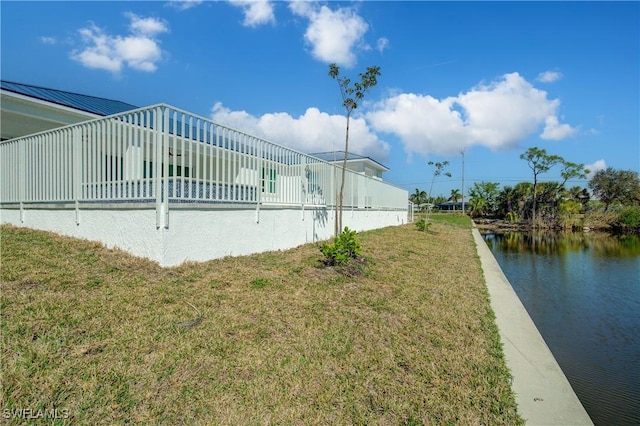 view of side of property with a water view, a standing seam roof, metal roof, and a lawn