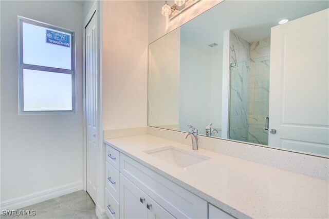 full bathroom with a marble finish shower, vanity, and baseboards