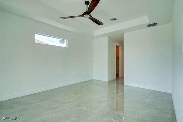 unfurnished room with baseboards, visible vents, ceiling fan, and a raised ceiling