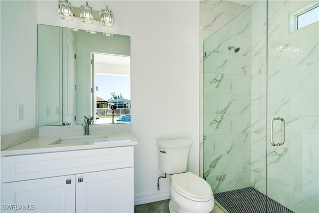 bathroom featuring baseboards, toilet, vanity, and a marble finish shower