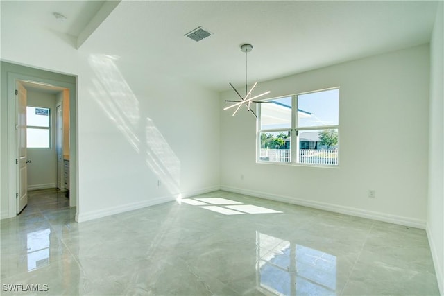 empty room with baseboards, visible vents, and a notable chandelier