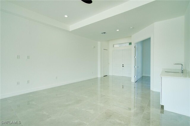 unfurnished room with visible vents, baseboards, a sink, and recessed lighting