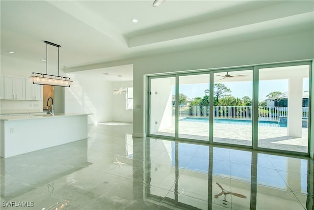 empty room featuring marble finish floor, a tray ceiling, a sink, and recessed lighting