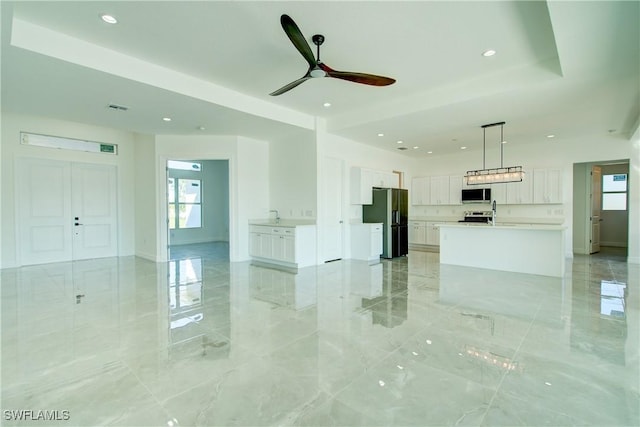 unfurnished living room featuring a tray ceiling, marble finish floor, recessed lighting, a sink, and ceiling fan